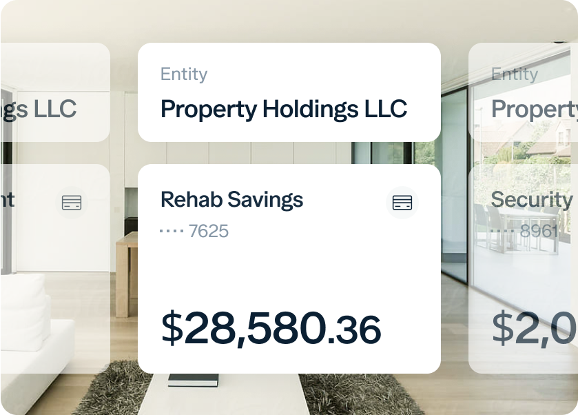A digital screen displays financial information, including an entity named "Property Holdings LLC" and an account titled "Rehab Savings" with a partial account number ending in 7625. The current balance of the account is $28,580.36. The background shows a modern, minimalist interior.