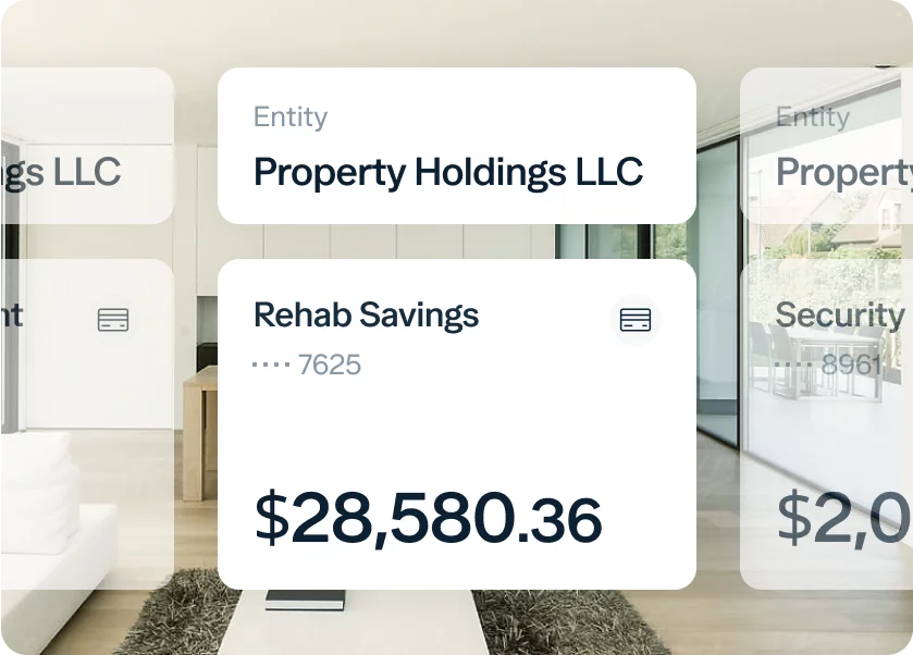 A digital screen displays financial information, including an entity named "Property Holdings LLC" and an account titled "Rehab Savings" with a partial account number ending in 7625. The current balance of the account is $28,580.36. The background shows a modern, minimalist interior.
