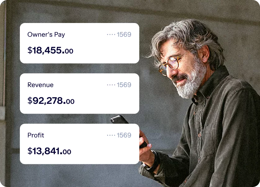 A person with gray hair and beard, wearing glasses and a button-up shirt, looks at a smartphone. Beside the person are three financial statistics: Owner’s Pay ($18,455.00), Revenue ($92,278.00), and Profit ($13,841.00).