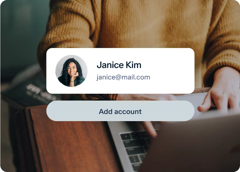 A person sits at a desk using a laptop. A digital overlay on the image shows a profile picture of a smiling woman, followed by the name "Janice Kim" and an email address "janice@mail.com." Below this, there is a button labeled "Add account.
