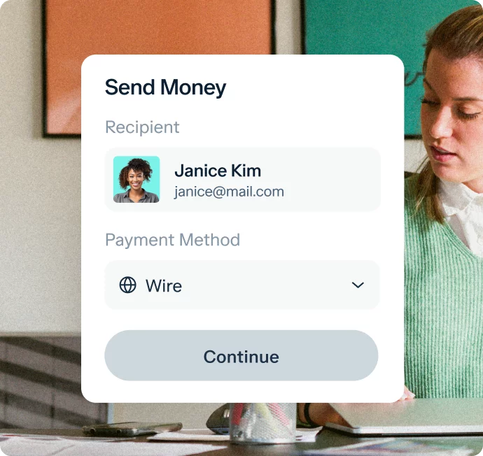 A mobile payment app interface shows the "Send Money" screen. The recipient is "Janice Kim" with an email address "janice@mail.com". The payment method selected is "Wire." An option to continue is also visible. In the background, a woman in a green sweater works.