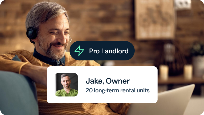 A man with gray hair and a beard, wearing an orange sweater and headset, smiles as he works on a laptop. Overlay text reads "Pro Landlord" and "Jake, Owner, 20 long-term rental units" with a small image of a man in a green shirt. The background shows a cozy, wooden room.