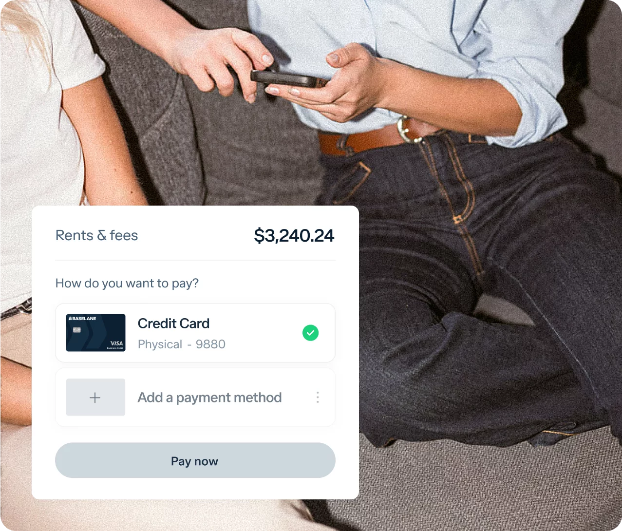 Two people are sitting on a couch, with an online payment interface displayed in the foreground. The interface shows a transaction for "Rents & fees" totaling $3,240.24 being paid by a credit card ending in 9880. One person is holding a phone.