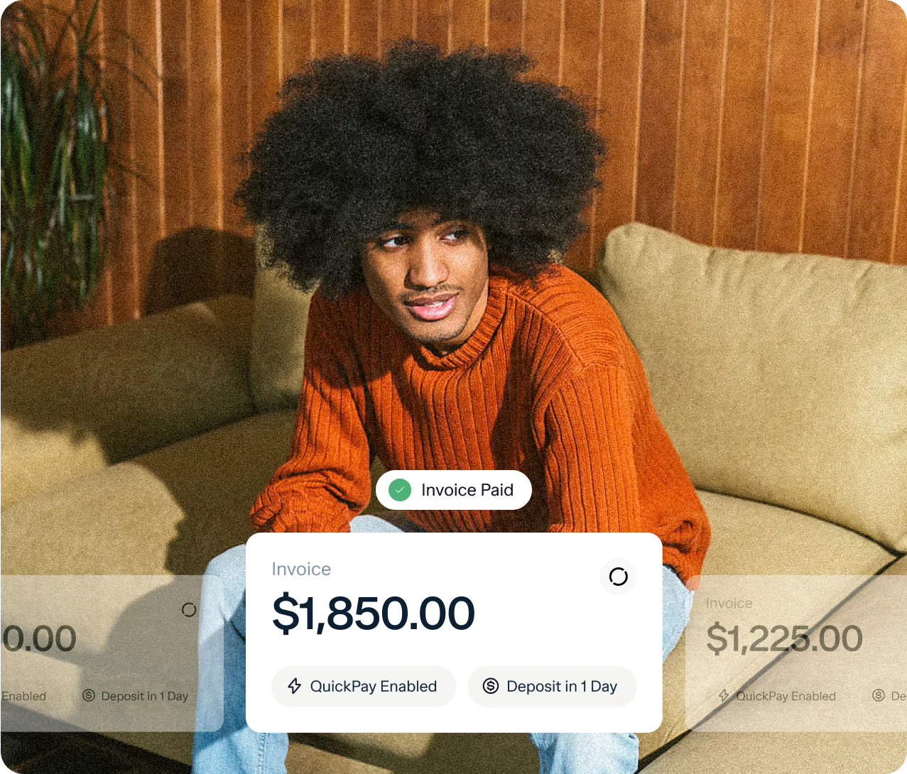 A person with an afro hairstyle, wearing an orange sweater, sits on a couch against a wooden wall. Overlaid on the image is a digital invoice indicating "$1,850.00" marked "Paid," with options for "QuickPay Enabled" and "Deposit in 1 Day.