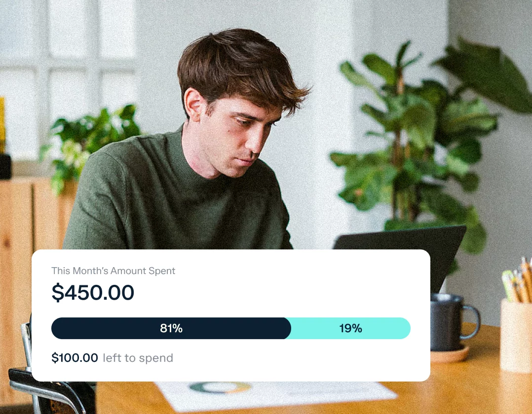 A person with brown hair, wearing a green sweater, is using a laptop at a desk. A spending bar chart overlay shows $450.00 spent this month, with $100 left to spend. The bar indicates 81% of the budget is used, with 19% remaining.