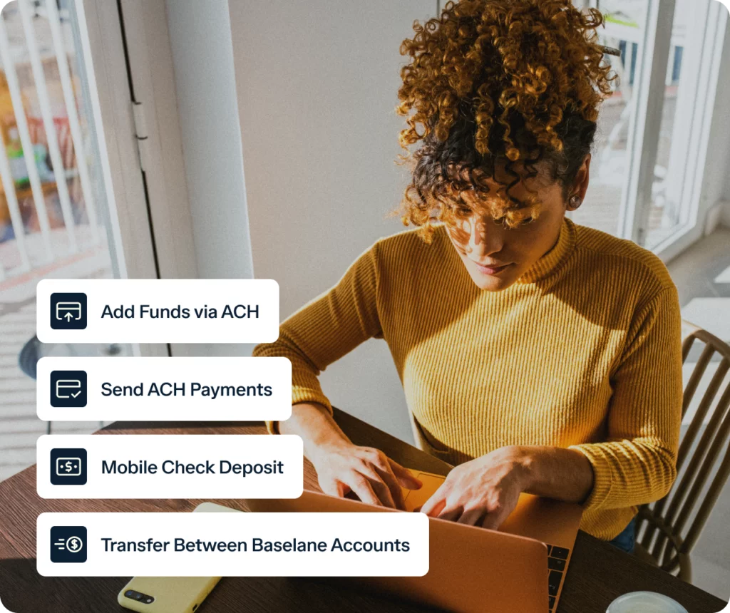 A person with curly hair in a yellow sweater uses a laptop at a table near a window. Four icons and text bubbles are displayed on the left, listing features: "Add Funds via ACH," "Send ACH Payments," "Mobile Check Deposit," and "Transfer Between Baselane Accounts.