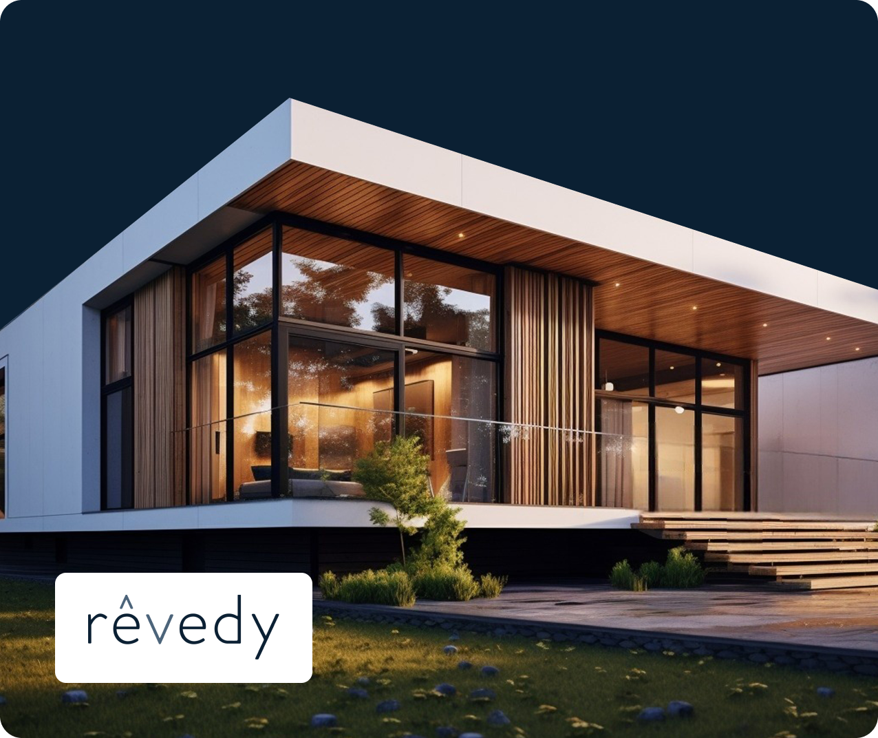 Modern house with large glass windows and wooden panel accents, surrounded by grass and small trees. The interior is warmly lit, visible through the windows. A logo with the text "rêvedy" is in the lower left corner.