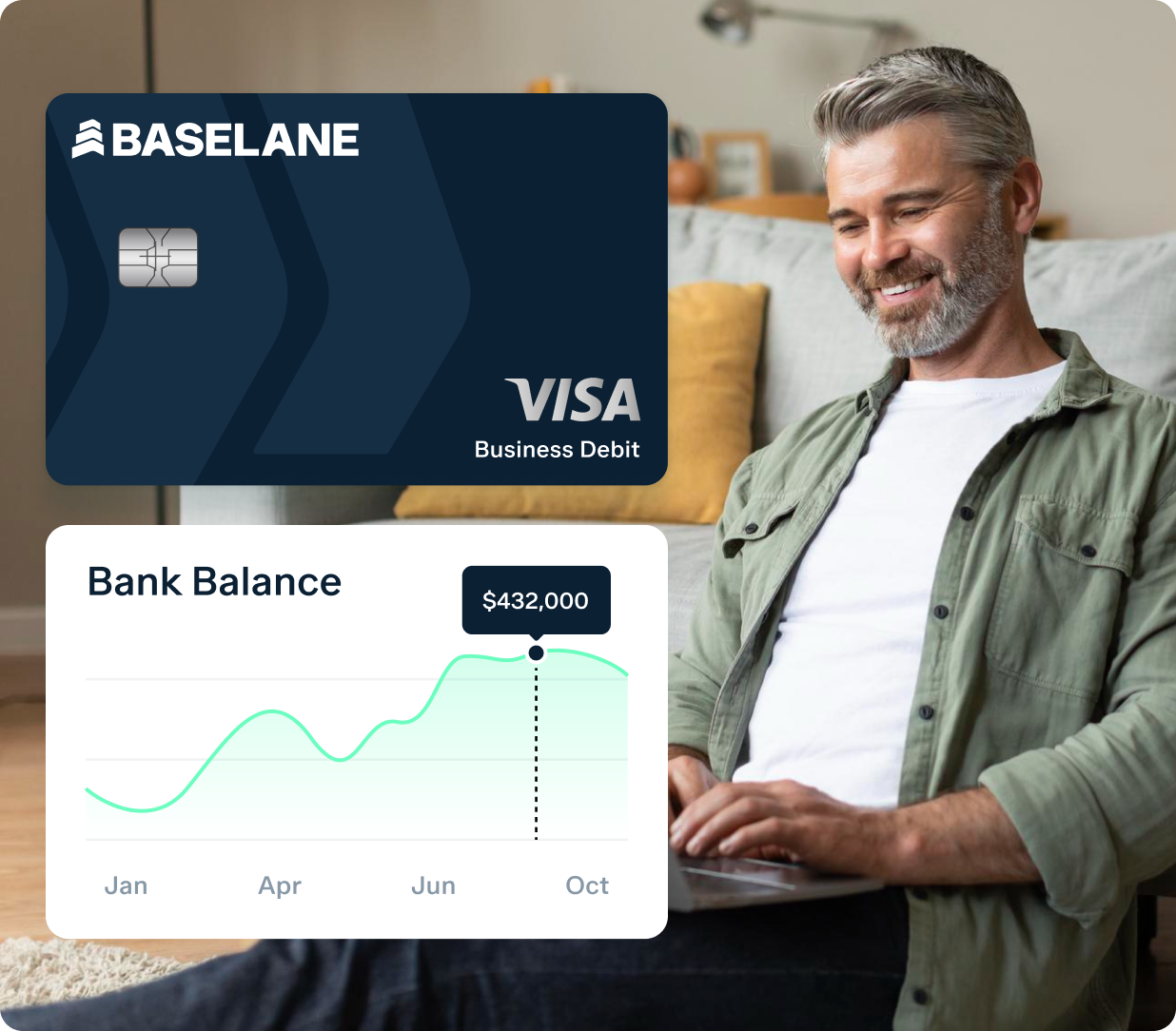 A man with grey hair and beard, wearing a casual shirt, is sitting on the floor with a laptop. A graphic shows a Baseline Visa Business Debit card and a bank balance chart peaking at $432,000 in October.