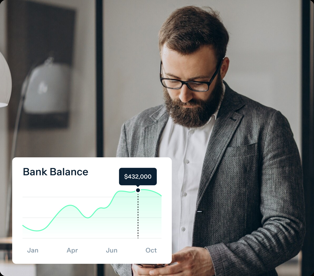 A man with a beard and glasses is looking at his smartphone. In the foreground, there is an overlay of a line graph titled "Bank Balance," showing a balance of $432,000 as of October, with fluctuating values from January through October.