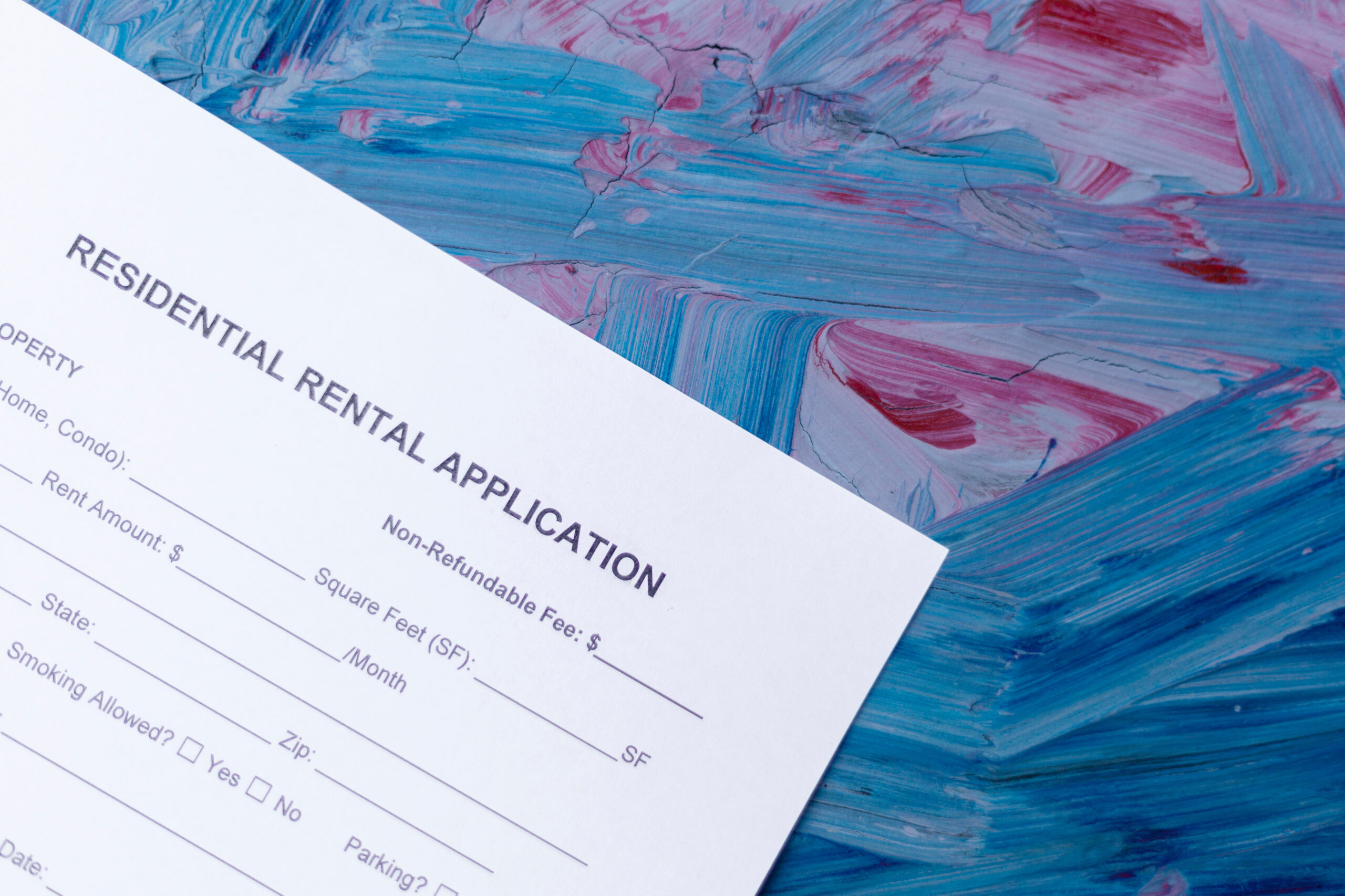 A residential rental application form partially visible on a colorful abstract background with blue, pink, and purple brushstrokes. The form asks for property details, rent amount, and additional features.