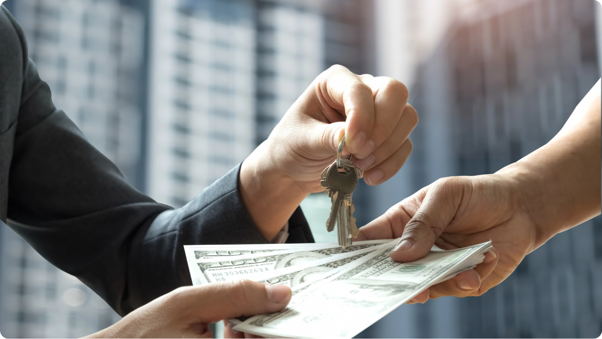 A person hands over a set of keys while receiving a stack of U.S. dollar bills, possibly as security deposit alternatives for real estate or a car, with blurred city buildings in the background.