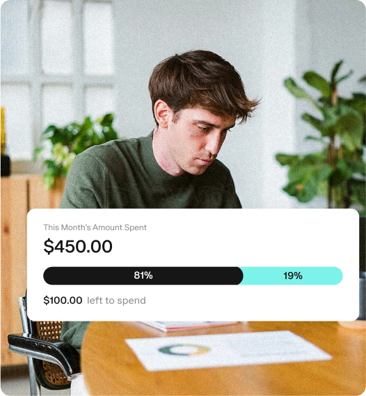 A man sits in an office looking at paperwork. In the foreground, a graphic shows he has spent $450 this month, with 81% spent and $100 left to spend. Plants and office furniture are in the background.
