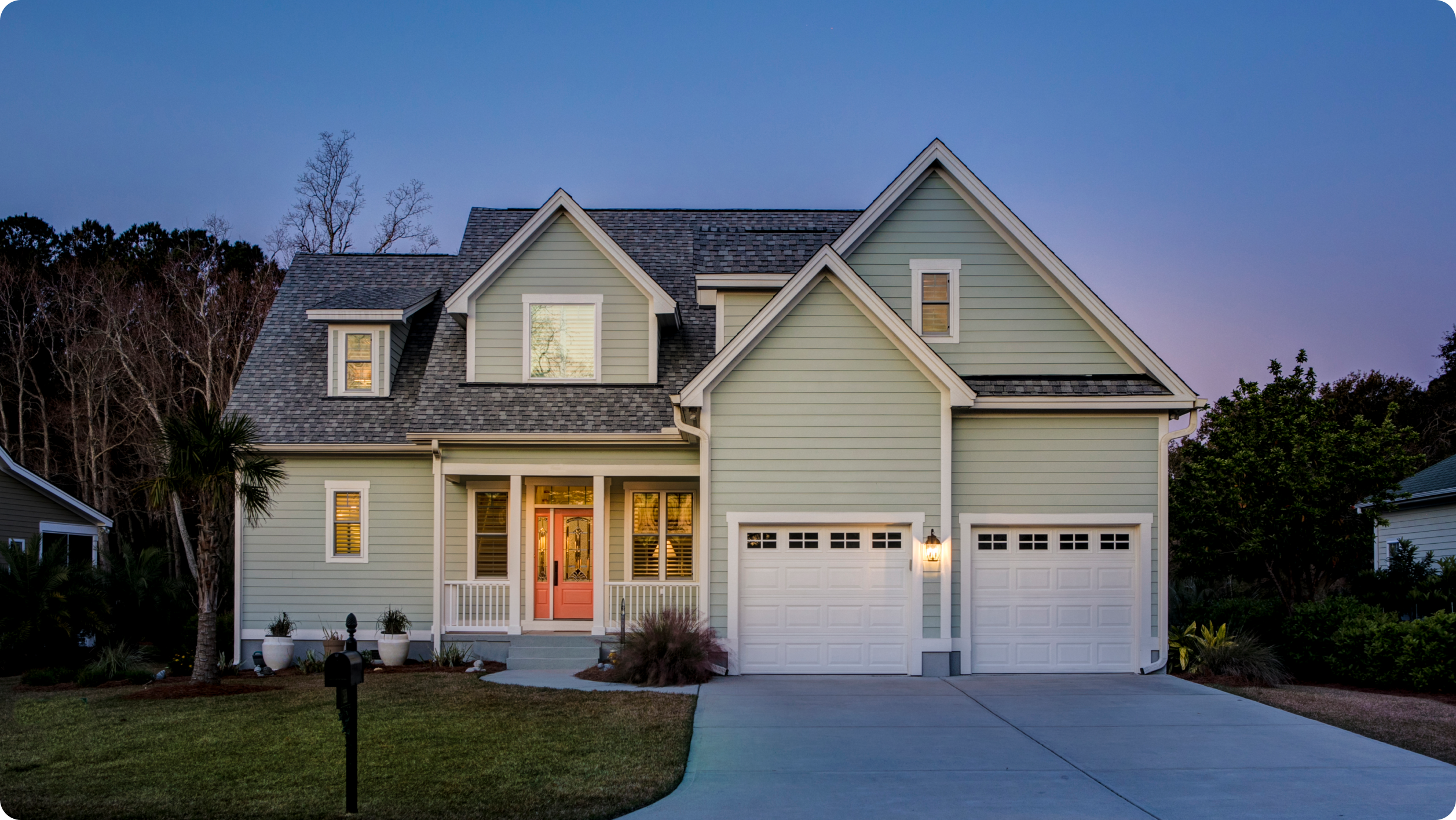 A modern two-story house with pale green siding, white trim, a pink front door, and a double garage stands on a well-kept lawn at dusk—ideal for families seeking comfort and eligible for HOA bank services.