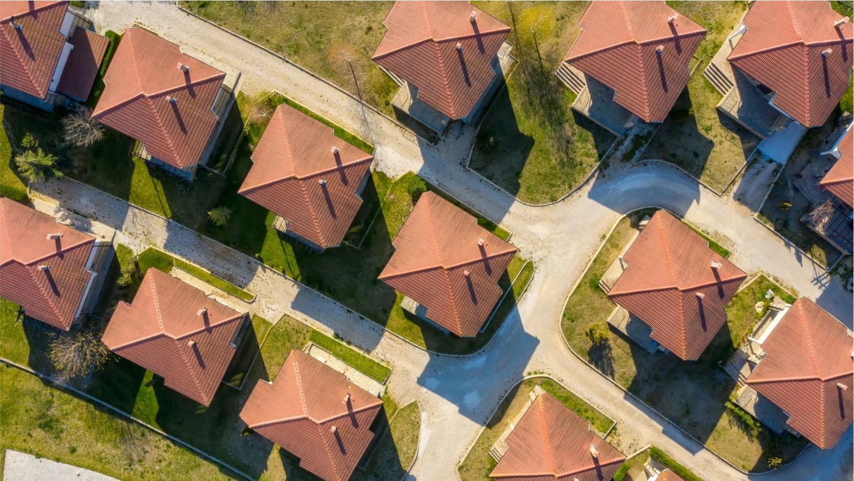 Aerial view of a suburban neighborhood with red-tiled roofs, arranged along winding roads—each home reflecting careful planning, much like choosing a business vs personal bank account for managing finances.